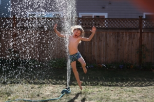Little boy jumping in a sprinkler