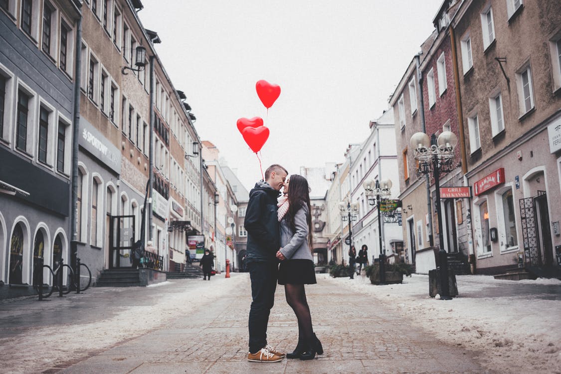 couple kissing in street with valentine's balloons