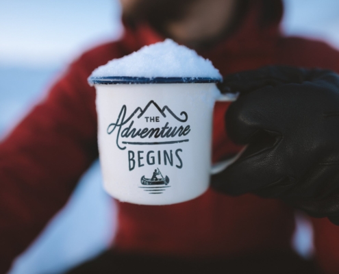 person holding mug filled with snow